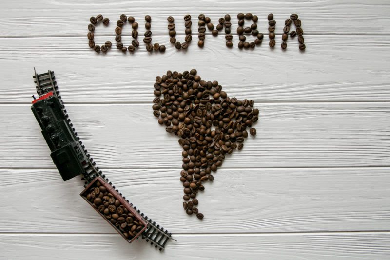 A wooden table topped with coffee beans and the word columbia.